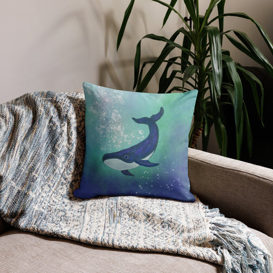 Decorative pillow with a whale design on a couch next to a plant.Whale presence of steady compassion and awareness