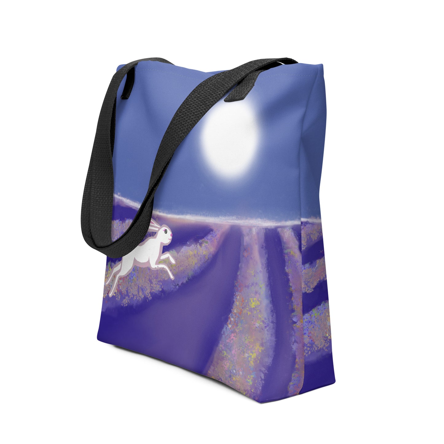 Side view Carry the magical spirit of the hare or rabbit with you. A spacious and colorful tote bag to help you carry around everything that matters. Design shows hare running through a field under a full moon. Blues, purples and white.