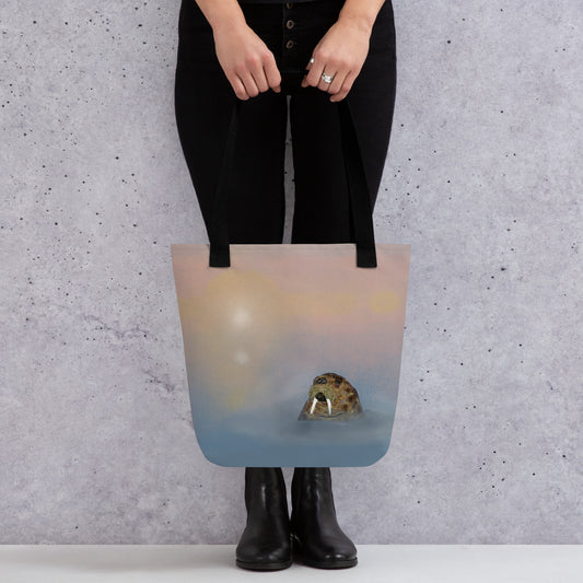 Walrus  on 15" x 15" tote bag. Gentle giant, spirit guide, medicine man. Walrus head popping out of the misty arctic sea. Product mockup shown being held by a woman wearing black and standing against a gray wall.