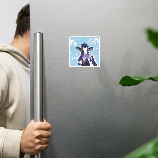 Image of a black and white cow against a blue sky on a die-cut-magnet. Shown on a refrigerator. Three sizes 3x3, 4x4, 6x6.