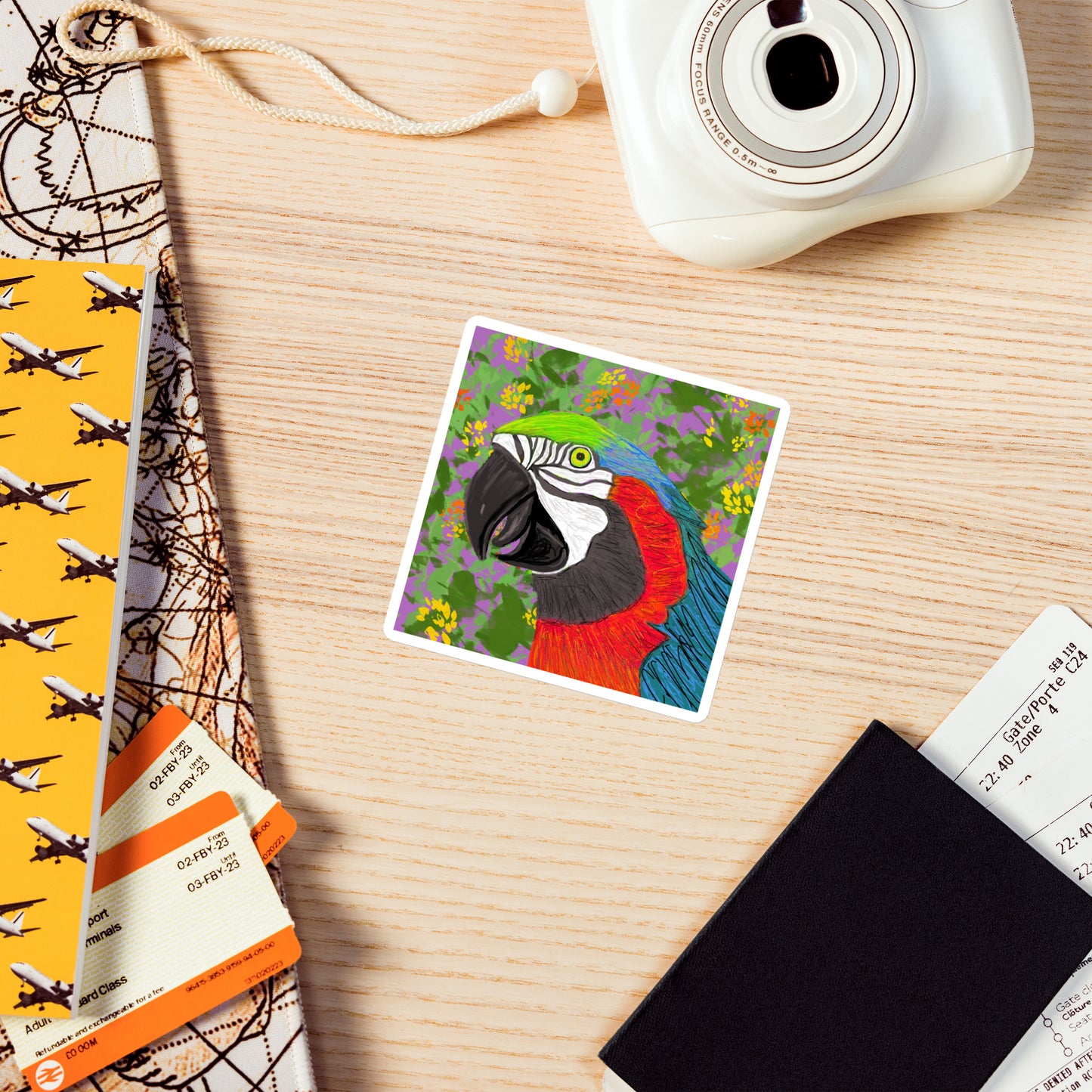 Colorful parrot illustration on a magnet with a camera and travel items on a wooden surface
