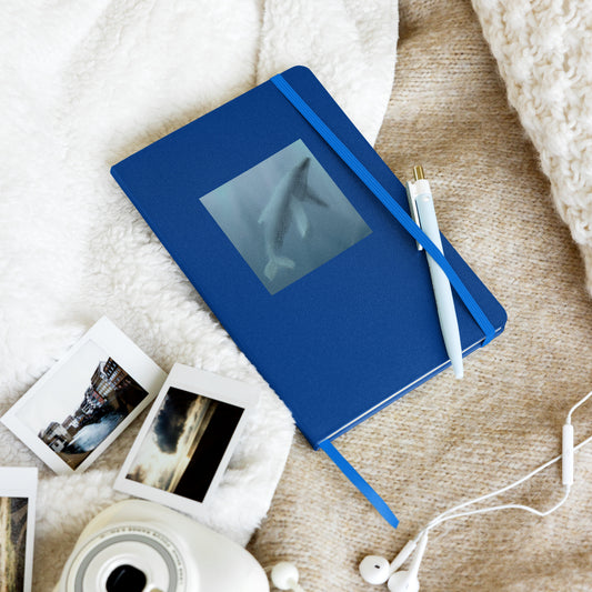 Blue notebook with image of whalemother and calf with photos and earphones. A guide through time, holding stories older than language.
