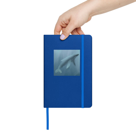 Blue notebook/journal with a whale illustration held by a hand on a white background