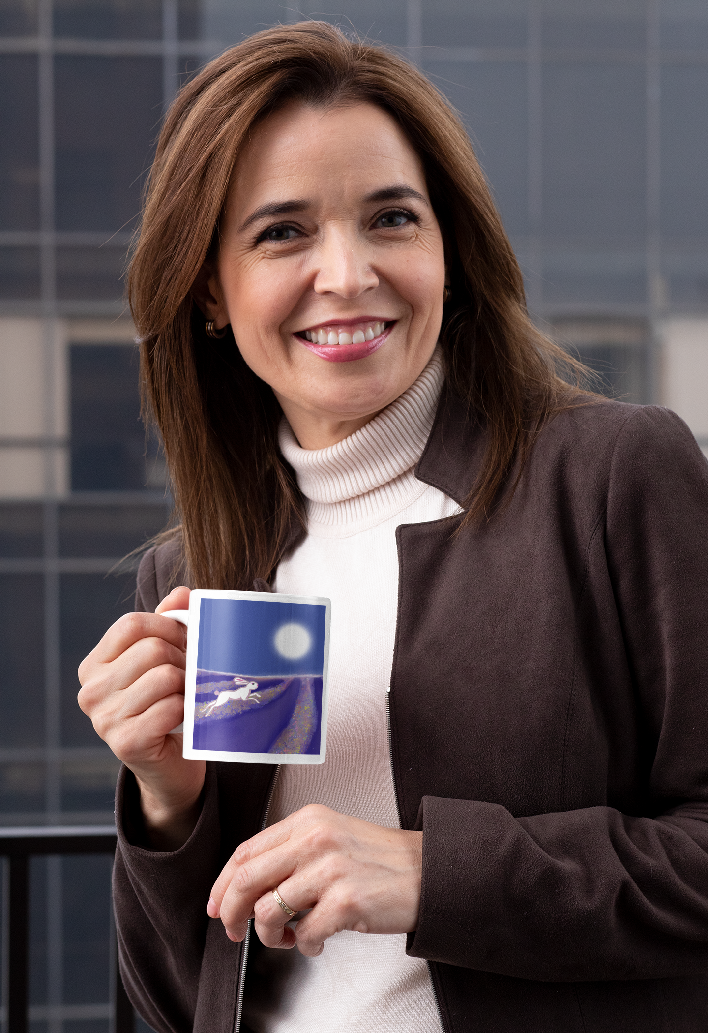 Woman in an office holding a mug with an image of a hare running through a lavender field under a full moon.