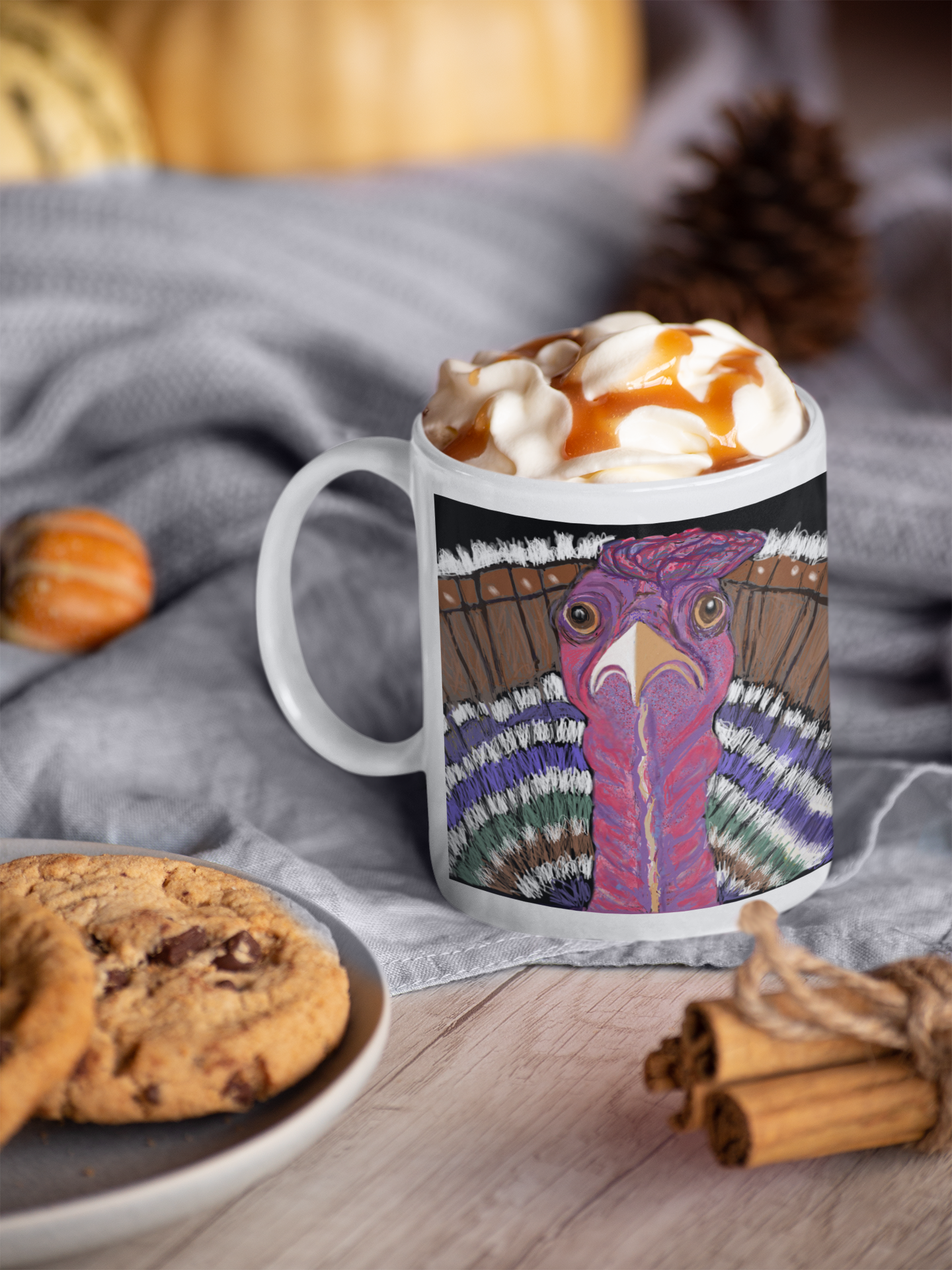 Mug with a colorful turkey design on a table with cookies and cinnamon sticks.