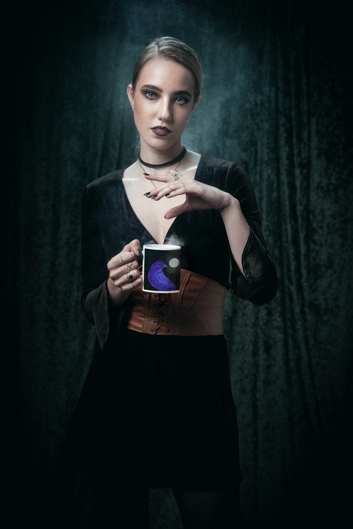 Woman in black holds a Crow mug as her hand touches the rising steam.