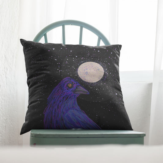 Decorative pillow with a golden-eyed crow and moon on a starry night, placed on a light blue chair.