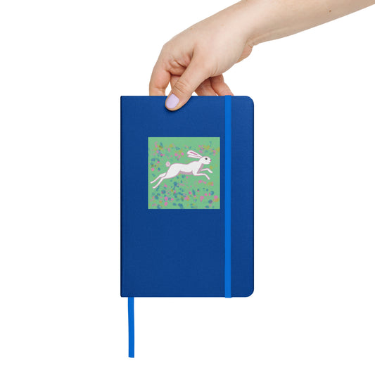 Blue notebook with a hare illustration held by a hand on a white background