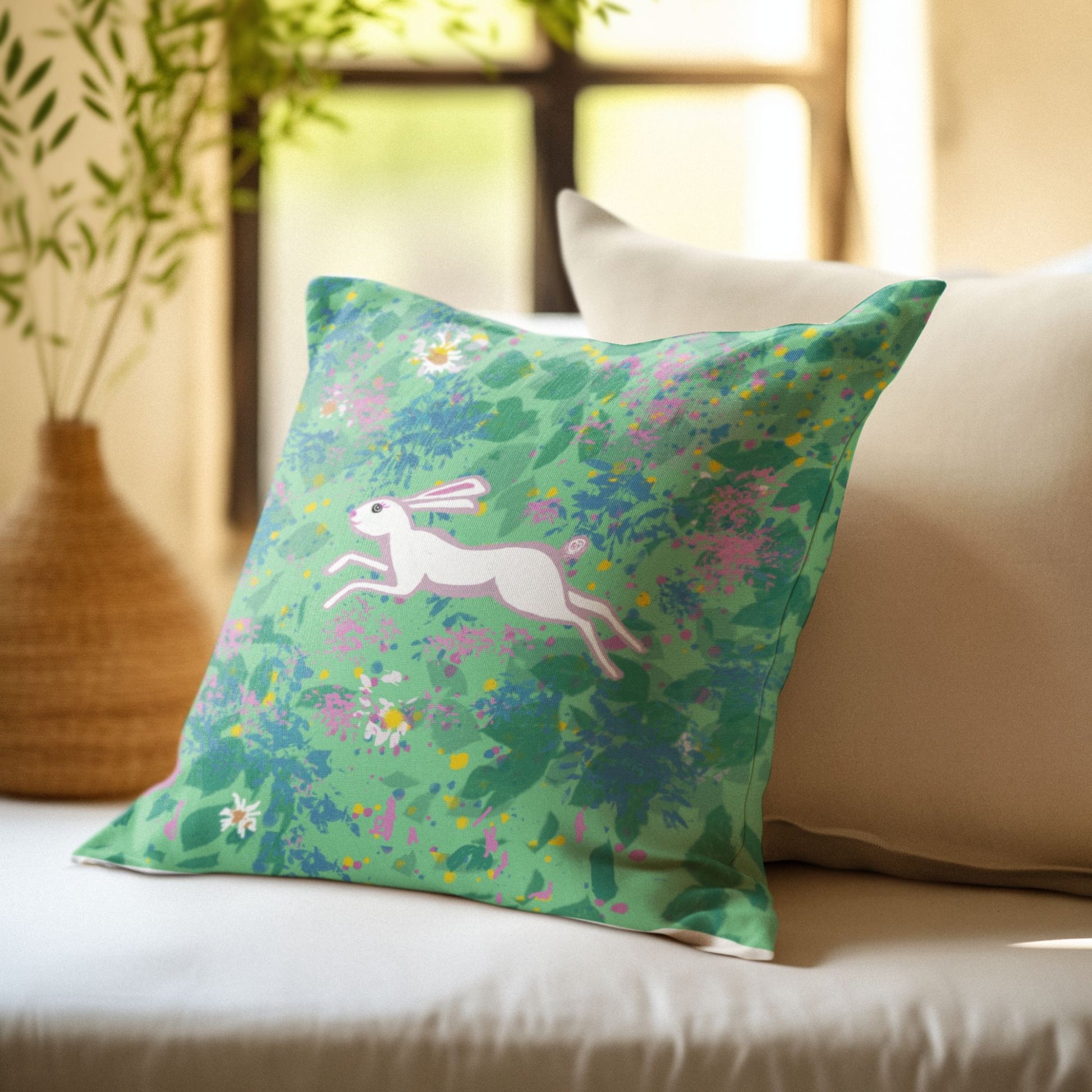 Decorative pillow with a hare running through of field of flowers design on a couch
