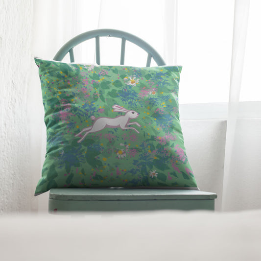 Green pillow with floral pattern and hare design sitting on a chair.