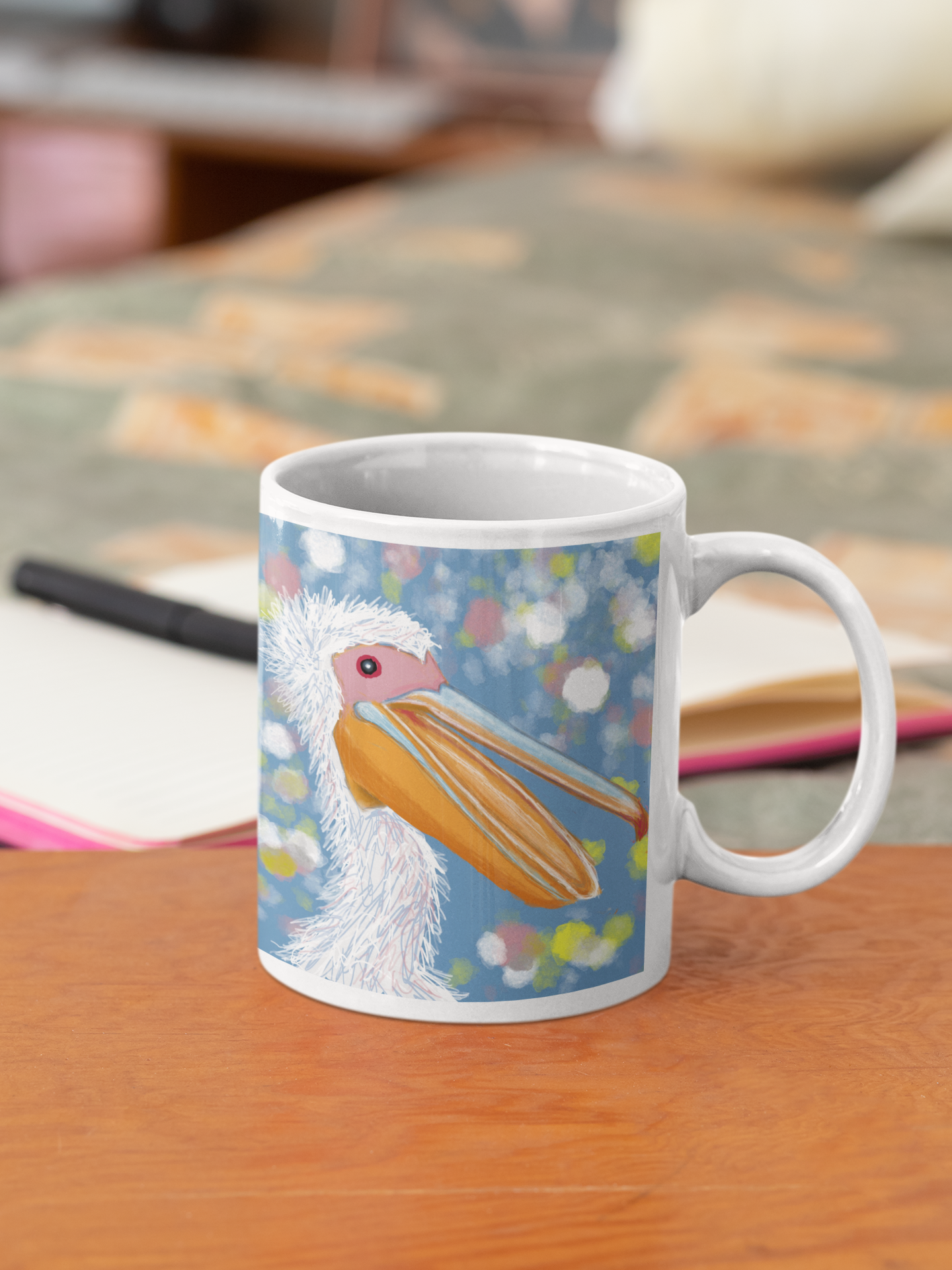 A colorful Pelican mug sits on a table next to a bed.