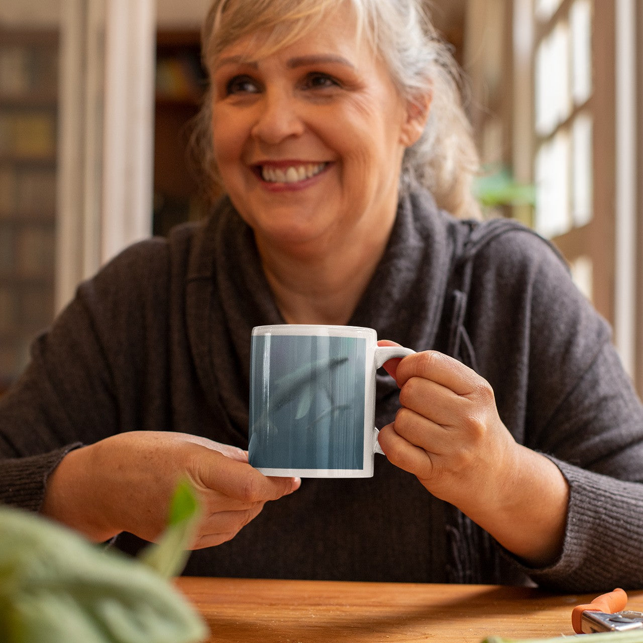 Grandmother holding a mug with an image of a Whale swimming in deep water with her calf.