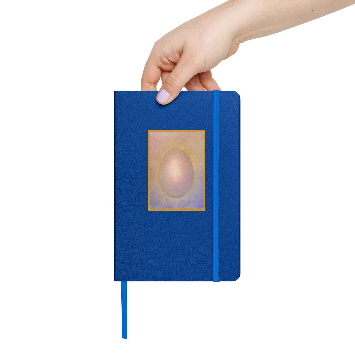 Hand holding a blue notebook with a original artists design of a penguin egg on the cover against a white background
