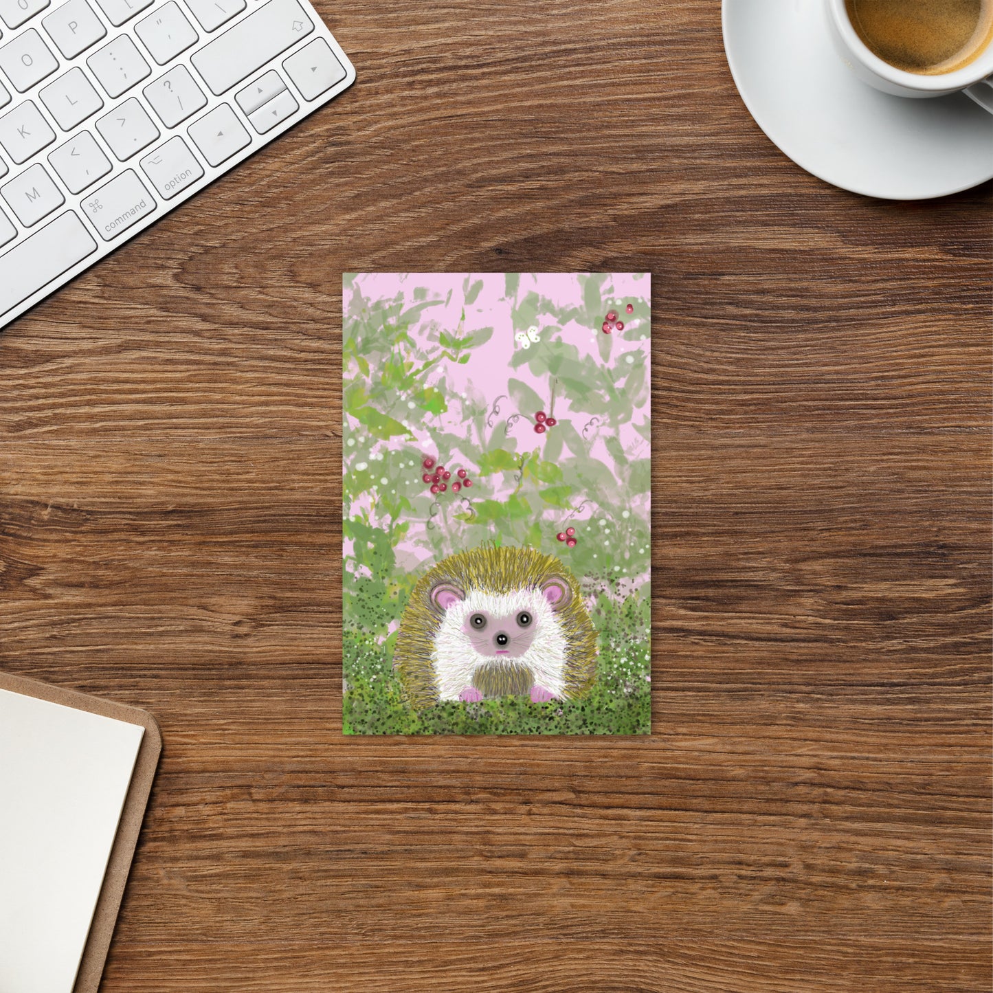 Sweet postcard with an image of the garden animal, the hedgehog.  Image shows hedgehog in a bramble of vines and berries, with a white moth. Hedgehog, with his sweet face, is gentle and kind spirit animal / spirit guide connected to Mother Earth. Standard size, 4x6,  postcard shown sitting on a desk. Vertical alignment