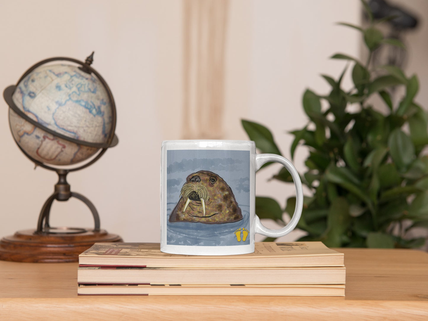 Premium ceramic coffee mug is a unique gift for animal lovers. The walrus looks around from his place in the sea. Shown here on a desk next to books and a globe.