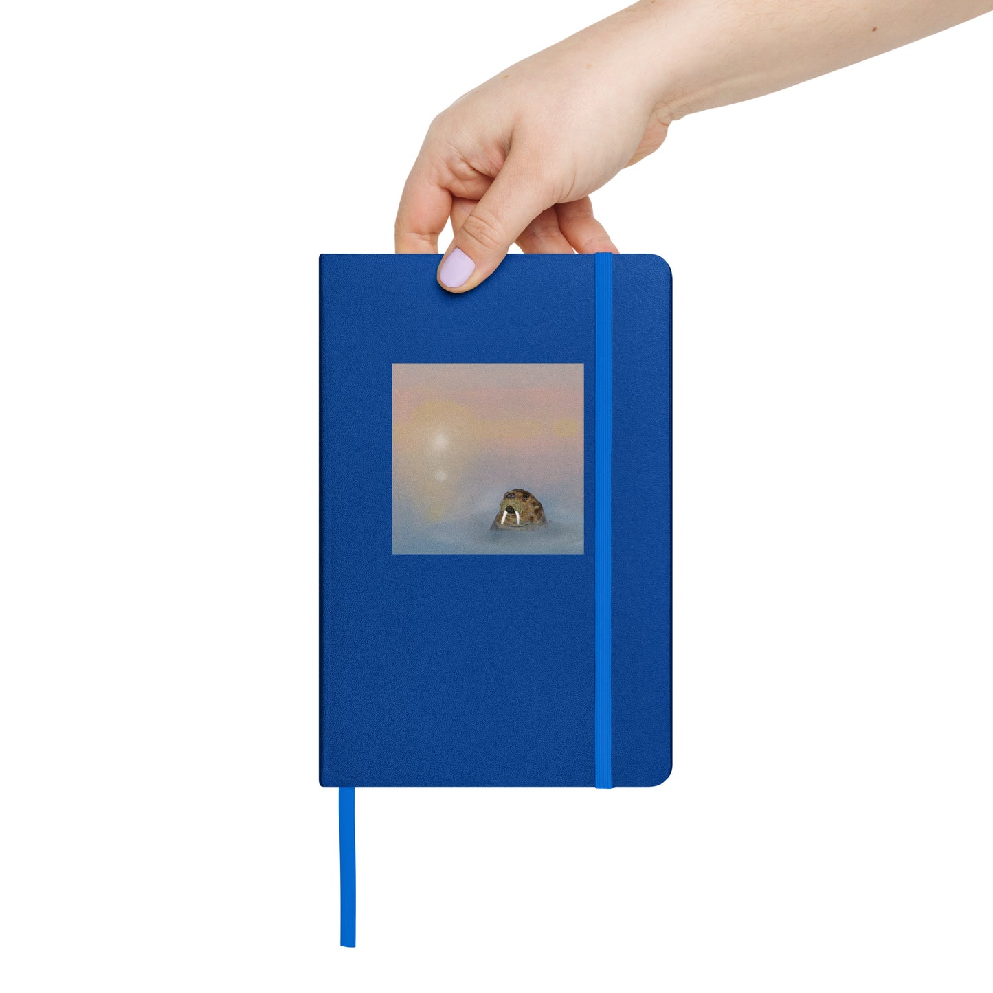 A hand holding a blue notebook with an image of a walrus bobbing in a misty sea. 