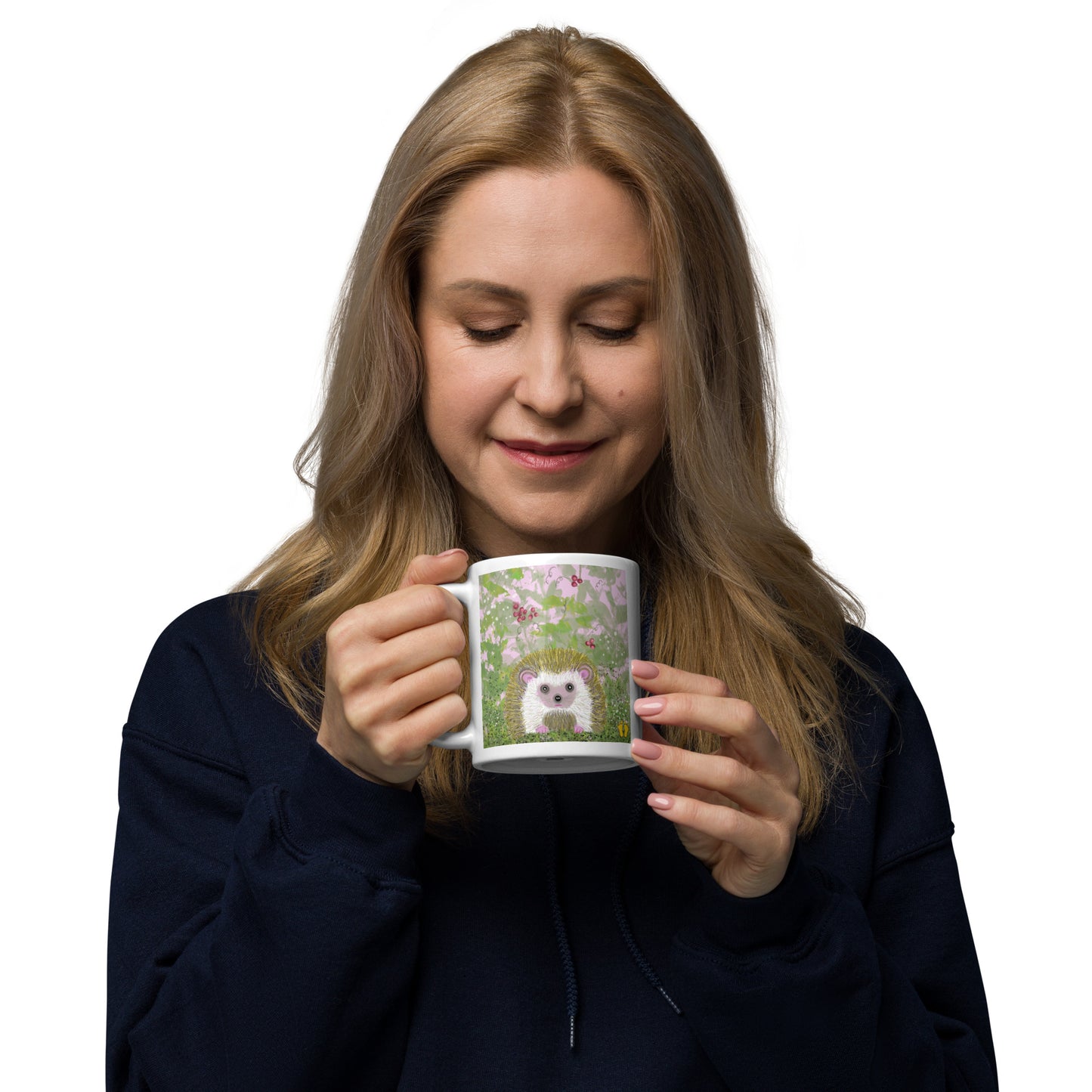 Smiling woman holds 11 oz. mug with an hedgehog design. Small garden animal shown in brambles--vines and berries. Hedgehog is gentle and kind spirit animal connected to Mother Earth.