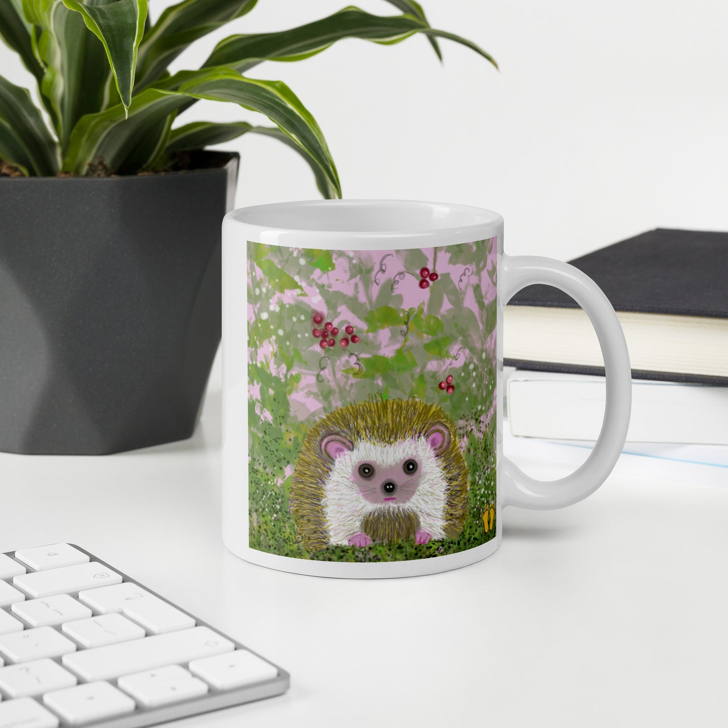 Ceramic mug with a hedgehog design sits on a desk. The garden animal on the mug sits in brambles--vines and berries and a white butterfly. Hedgehog is gentle and kind spirit guide connected to Mother Earth.