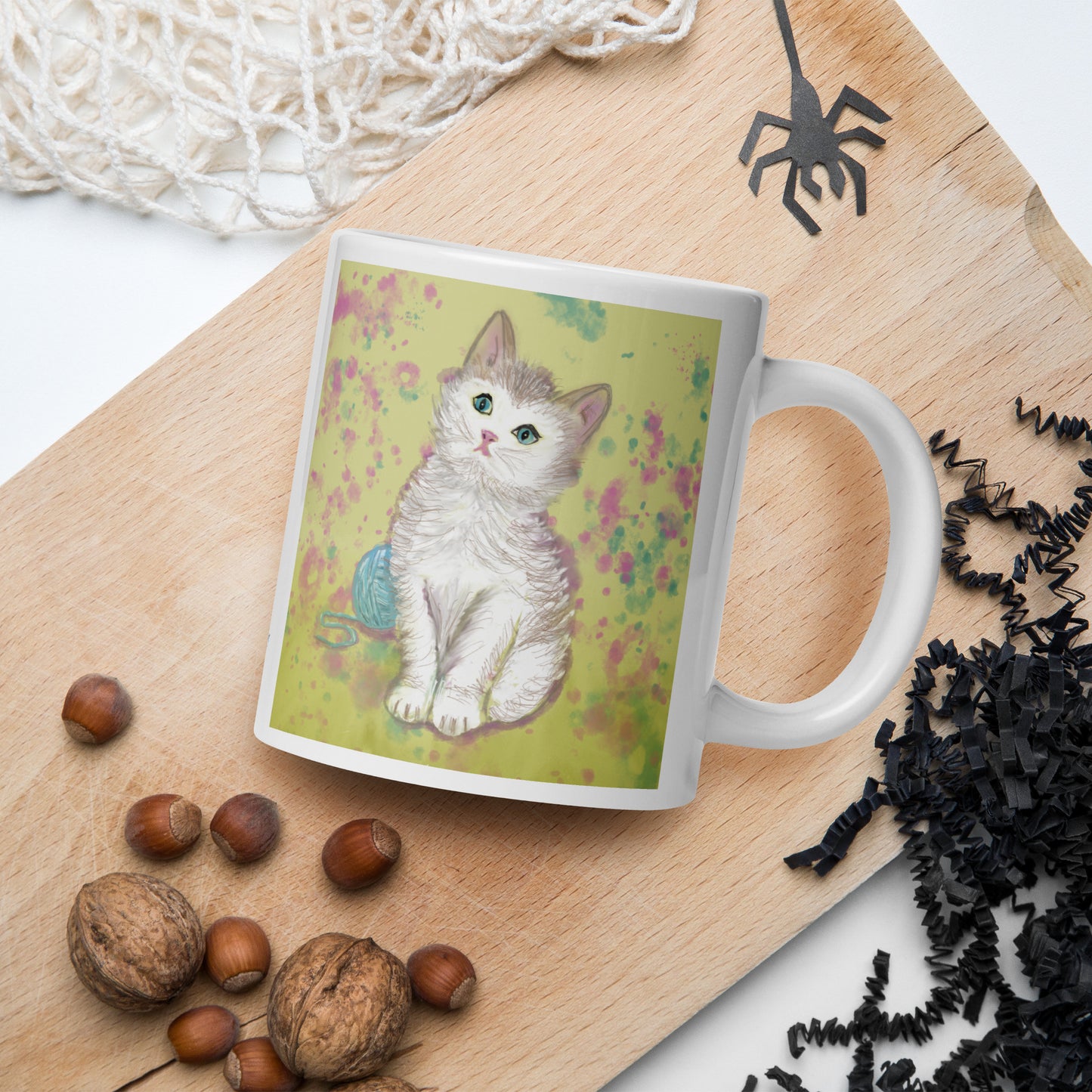 Mug with a Kitten Spirit design on a wooden surface with nuts and spider decorations.