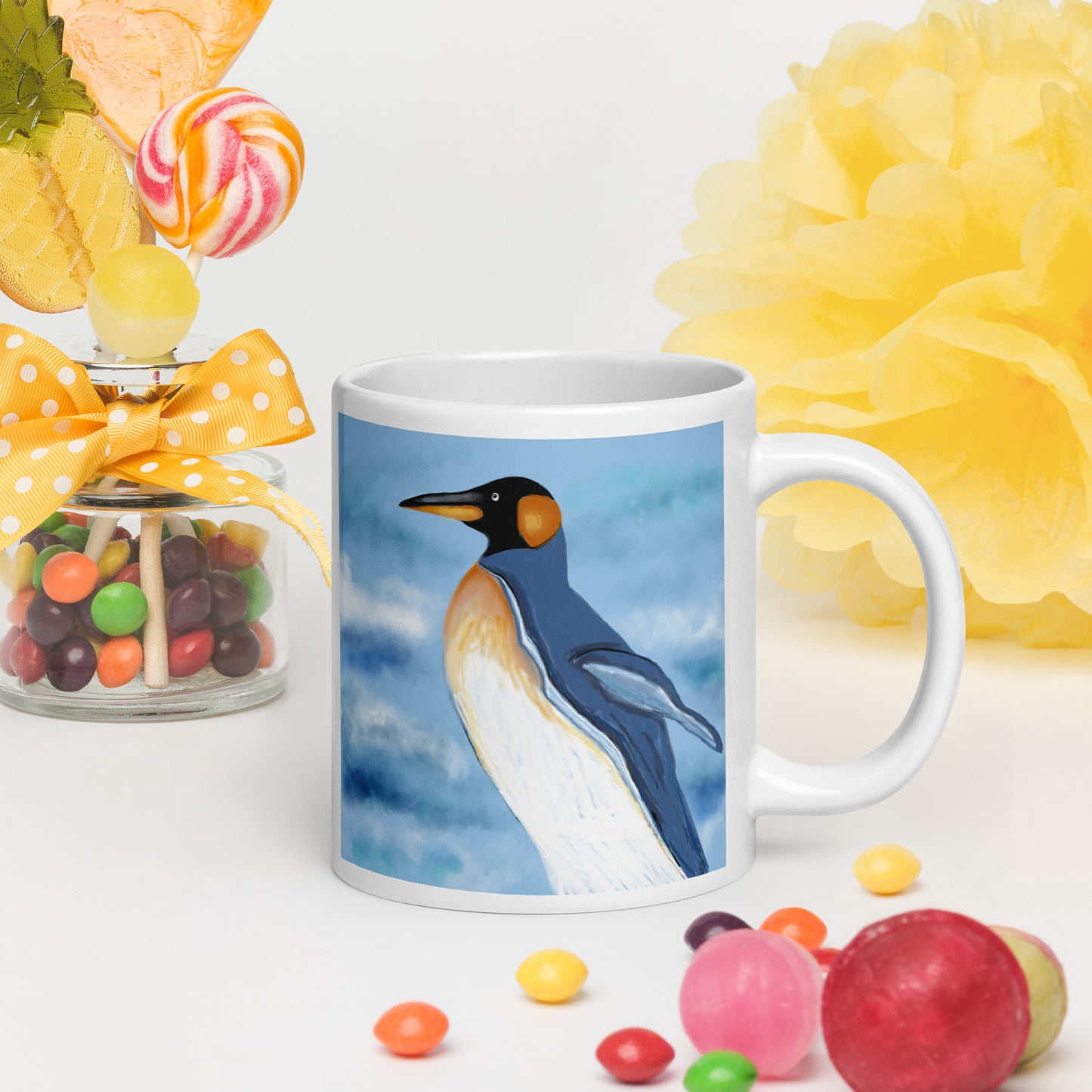 Mug with a penguin design surrounded by colorful candies and flowers. 20 oz