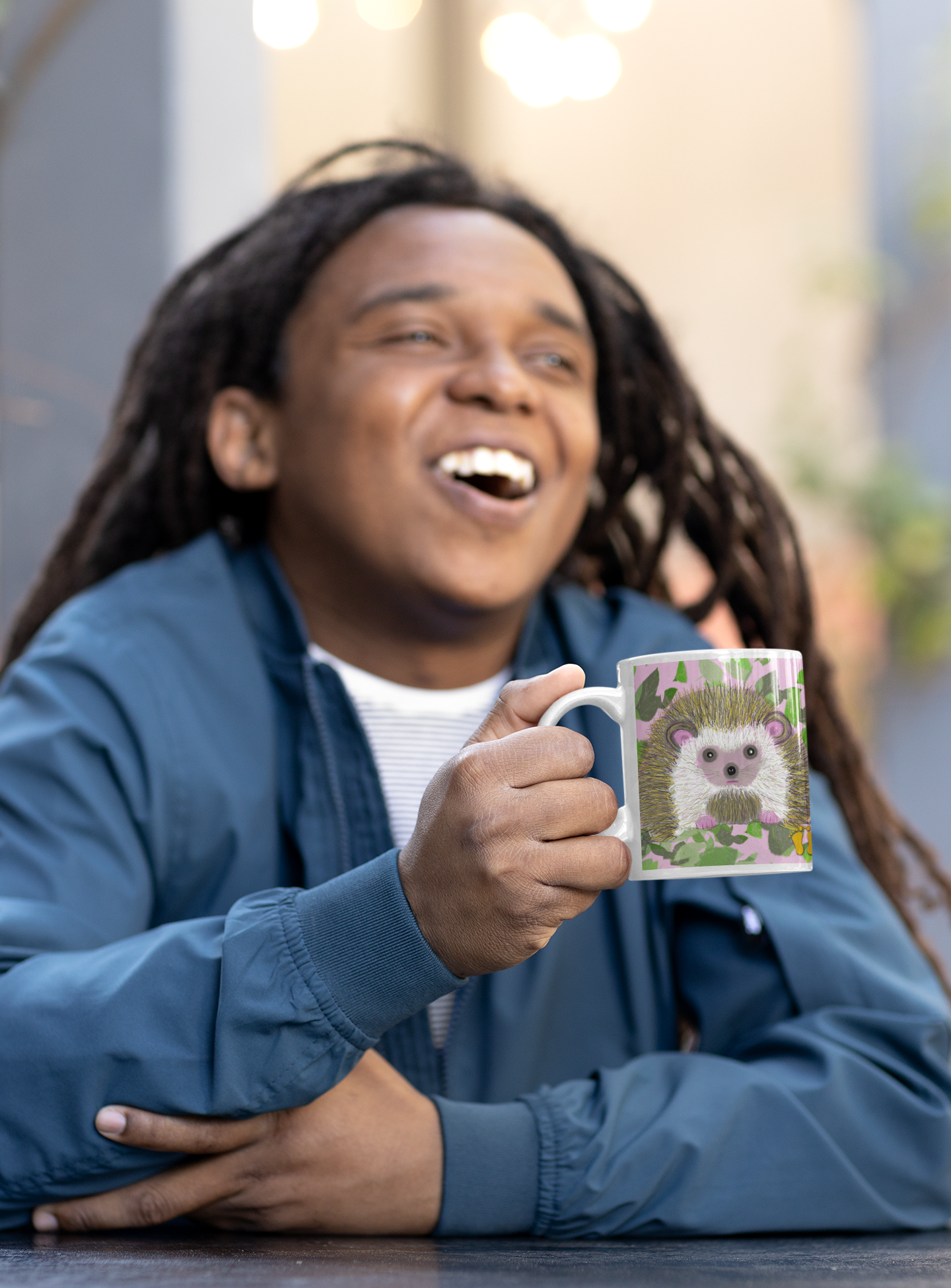 Is this original design of a cow on a mug by PittaPat your spirit animal? The cow  mug is shown here being held by a laughing man in a cafe enjoying his coffee break. 