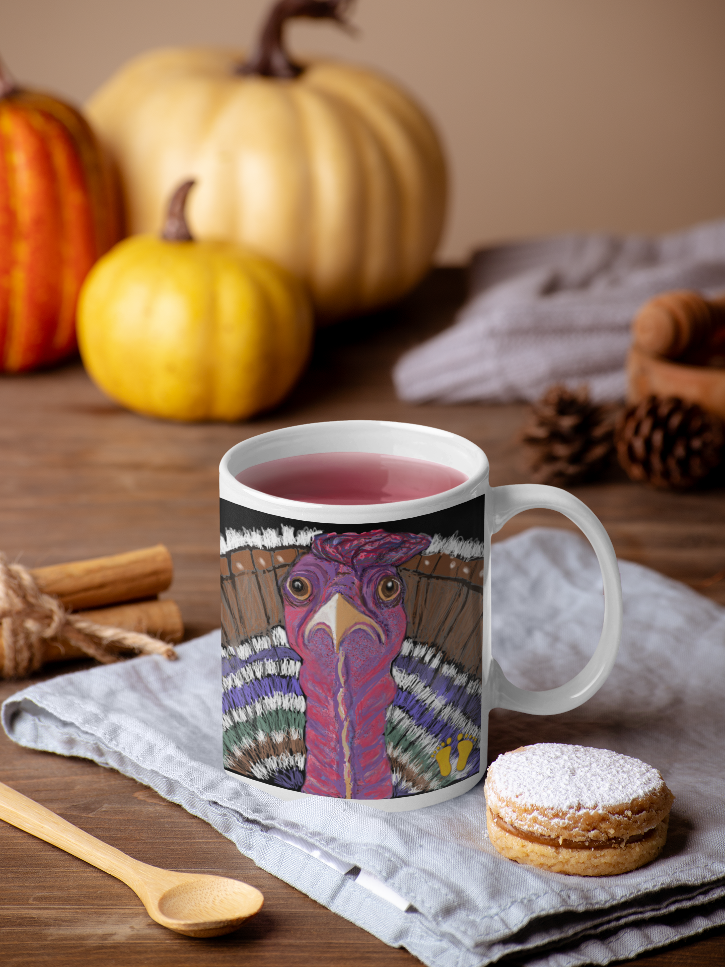 Premium ceramic coffee mug is a unique gift for animal lovers. Brightly colored turkey is shown with a long neck and tail feathers. Shown here on a table decorated with pumpkins and cinnamon.